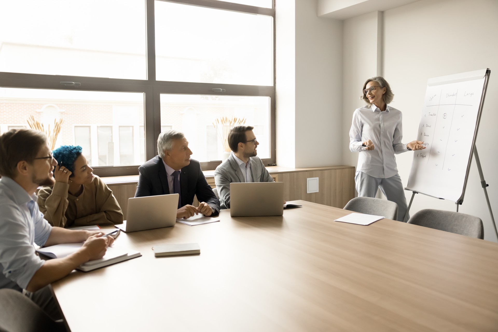 Confident mature businesswoman presenting project plan to diverse team